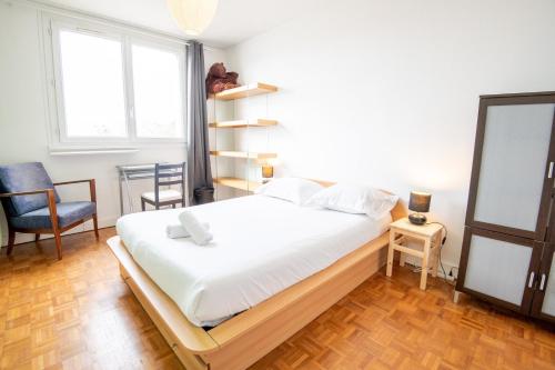 ein Schlafzimmer mit einem großen weißen Bett und einem Stuhl in der Unterkunft Le Botanique - Joli appart à Tours in Tours