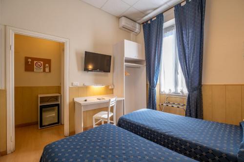 Cette chambre comprend deux lits et un bureau. dans l'établissement Hotel Corso, à Sanremo