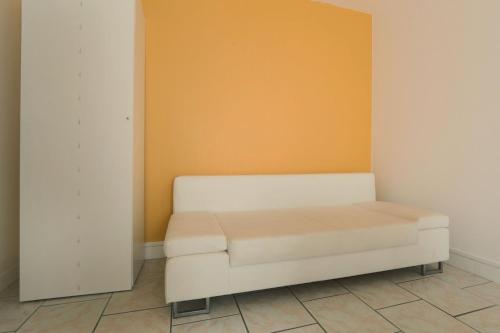 - un canapé blanc dans une chambre avec un mur orange dans l'établissement La Chanterie, à Saint-Cyr-sur-Loire
