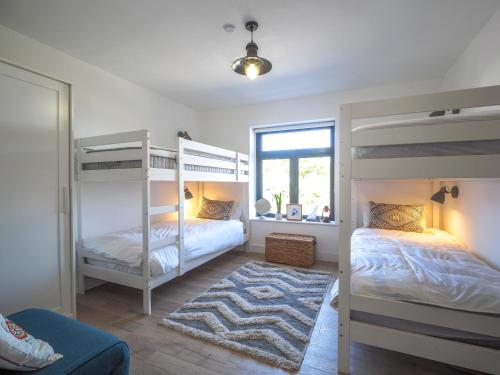 a bedroom with two bunk beds and a rug at Ty Machlud Tresaith in Penbryn