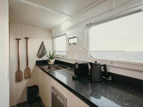 uma cozinha com um balcão, um lavatório e uma janela em Waterfront Houseboat em Cidade do Cabo