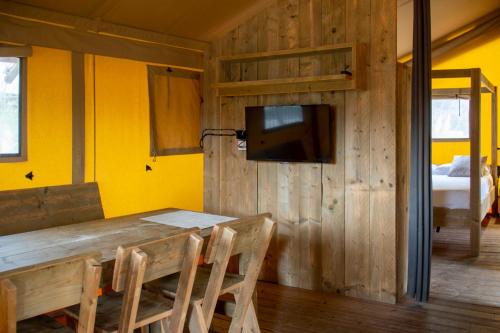 a dining room with a wooden table and a tv at Sangulí Camping & Resort in Salou