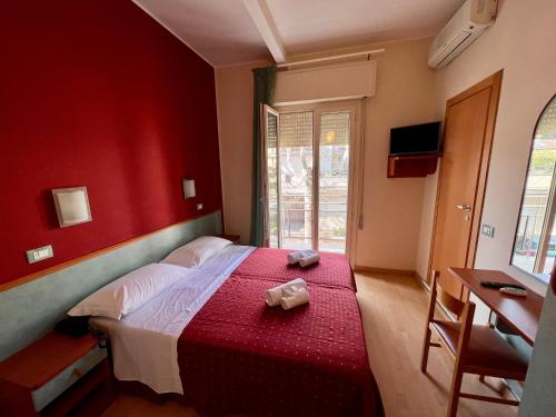 a red bedroom with a bed with a red wall at Hotel Villa Tina in Cesenatico