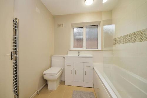 a white bathroom with a toilet and a bath tub at Beautiful home close to town Free Netflix, Wifi in Solihull