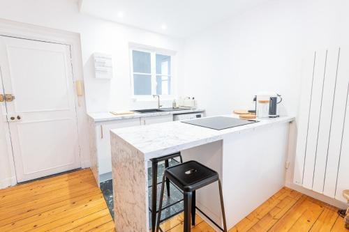 une cuisine blanche avec un comptoir et un tabouret dans l'établissement Le Petit Amandier - Tours, à Tours