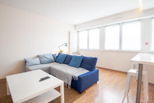 un salon avec un canapé bleu et des fenêtres dans l'établissement Le Globe Trotter - Tours, à Tours