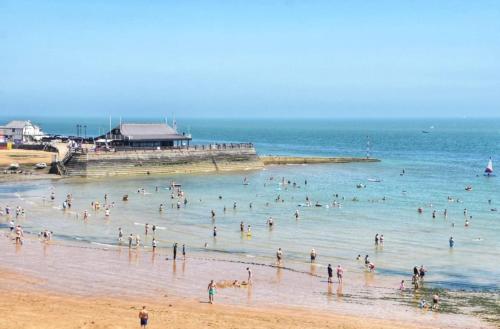 a group of people in the water at a beach at Bright, Seaview Apartment, Beachfront, 3 bedrooms, 2 bathrooms, kid & dog friendly at The Lookout Broadstairs in Broadstairs