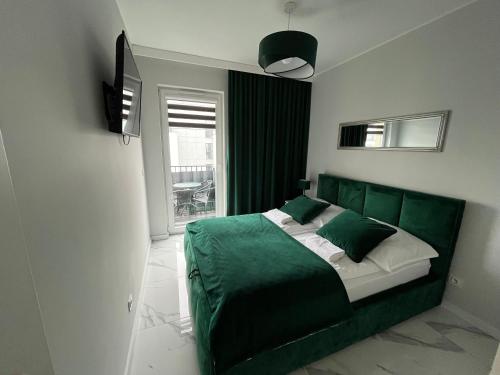 a bedroom with a green bed and a window at Apartamenty u Edyty in Jastrzębia Góra