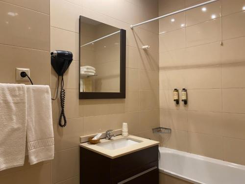 a bathroom with a sink and a mirror and a tub at Hotel Dom Afonso - Monção in Monção