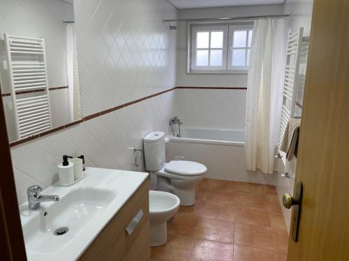 a white bathroom with a toilet and a sink at Casa do Olival in Tarouca