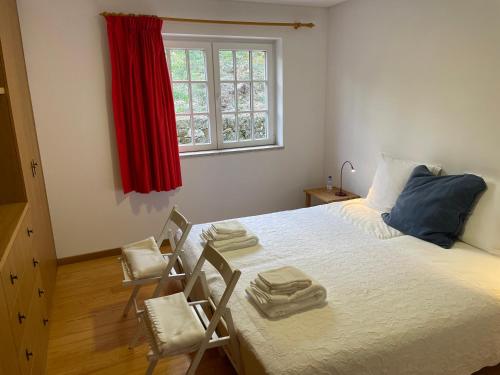 a bedroom with a bed with two chairs and a window at Casa do Olival in Tarouca