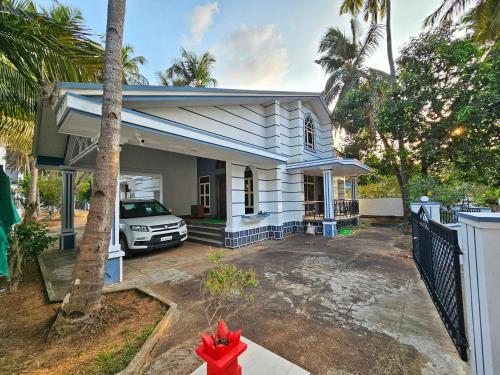 a white house with a car parked in front of it at Sirimudi Villa in Kundapur