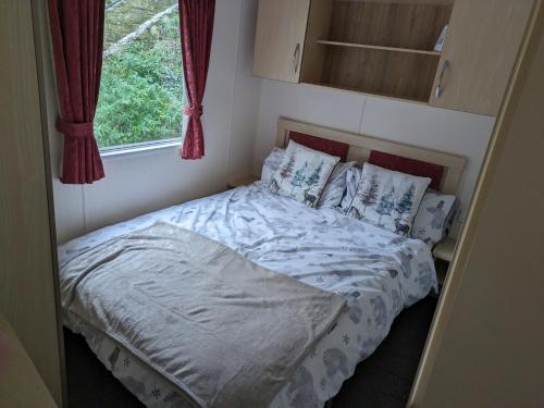 a bed in a small room with a window at Homely 2 bed caravan sleeps 4 5 in Portland Dorset in Portland