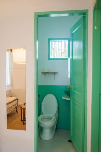 uma casa de banho com WC e uma porta verde em The Bard's Nest em General Luna