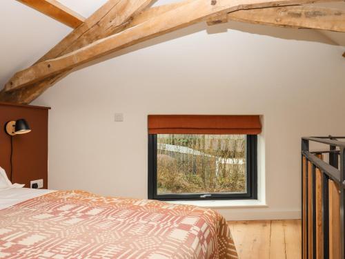 a bedroom with a bed and a window at 3 Caddaford Barns in Buckfastleigh