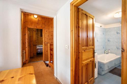 bagno con porta in legno, vasca e lavandino di Casa Vacanza Menfrey a Verrayes