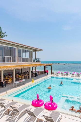 a swimming pool with chairs and the ocean in the background at LOVE beach club Koh Samui in Chaweng