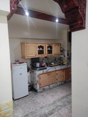 - une cuisine avec des placards en bois et un réfrigérateur blanc dans l'établissement Appartement situé à 5 minutes à pied de l'Aeroport de Marrakech, à Marrakech