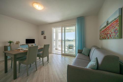 Milena Suite Apartments في ألغيرو: غرفة معيشة مع طاولة وأريكة وغرفة طعام