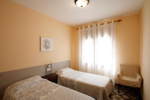 a room with two beds and a window with a chair at Villa Fortuna in Miami Platja