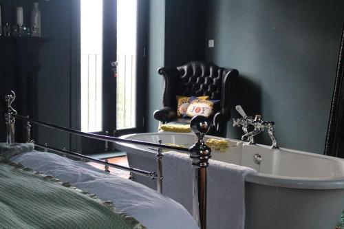 a bedroom with a tub with a chair and a mirror at BOHOUSE Moody boho townhouse Macclesfield centre in Macclesfield