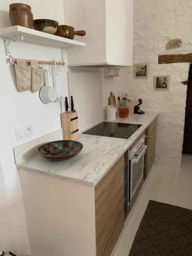 une cuisine blanche avec une plaque de cuisson sur le comptoir dans l'établissement Maison Le Haut Fée, 