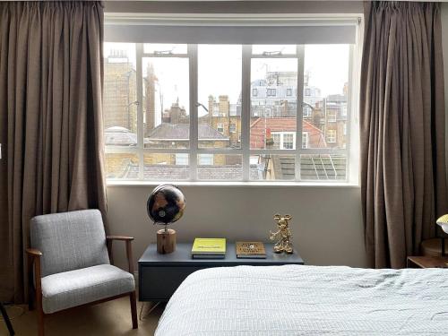 倫敦的住宿－Cozy apartment in Marylebone，卧室配有床、椅子和窗户。