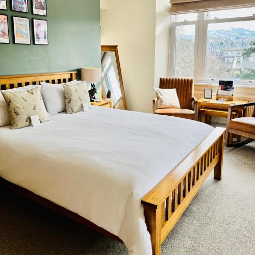 a bedroom with a large white bed with a table at The Devonian in Ilfracombe