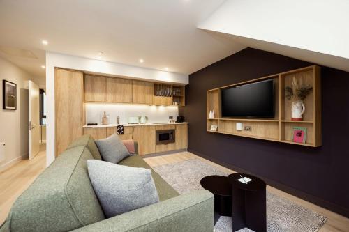 a living room with a couch and a tv at Wilde Aparthotels Edinburgh Grassmarket in Edinburgh