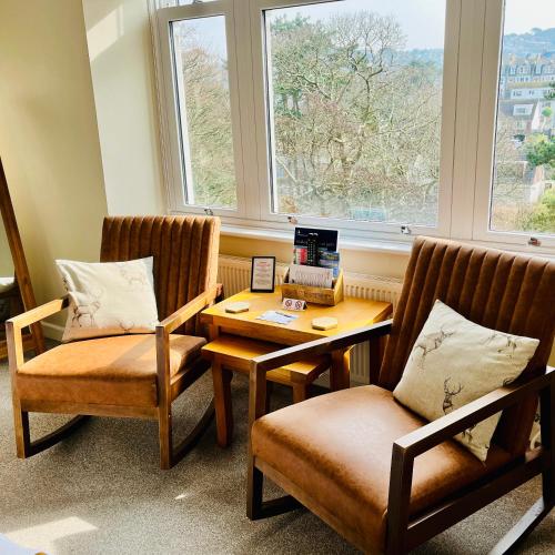 a room with two chairs and a table and two windows at The Devonian in Ilfracombe