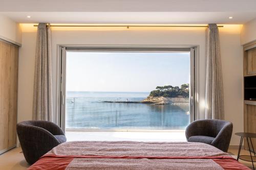 een slaapkamer met een groot raam met uitzicht op de oceaan bij VILLA LA ROMANELLA in Carry-le-Rouet