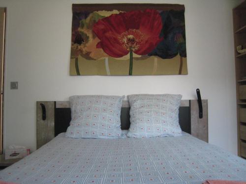 - une chambre avec un lit orné d'un tableau de fleurs rouges sur le mur dans l'établissement Bienvenue à Saint Prix, à Saint-Prix
