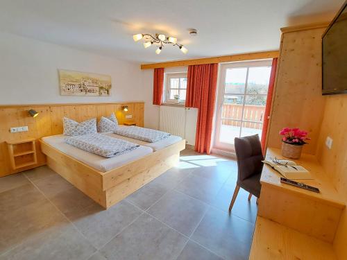 een hotelkamer met een bed, een bureau en een raam bij Pension Carina in Füssen