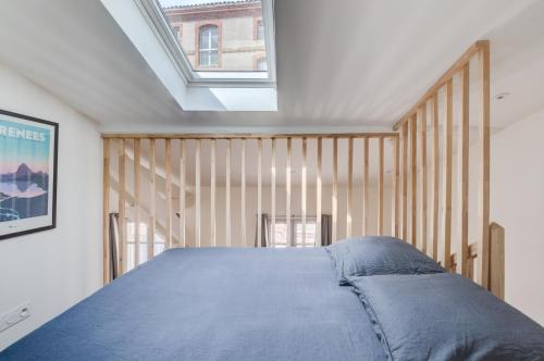 une chambre avec un grand lit avec une lucarne dans l'établissement Style et caractère, climatisation, à Toulouse