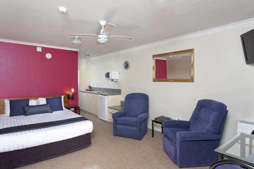 a bedroom with a bed and two blue chairs at BK's Rotorua Motor Lodge in Rotorua
