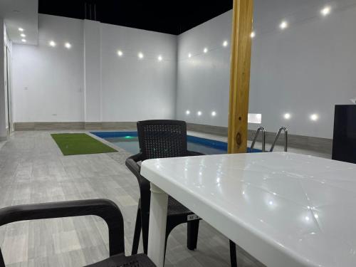 a white table and chairs in a room with a pool at Hurin Hotel in Ica