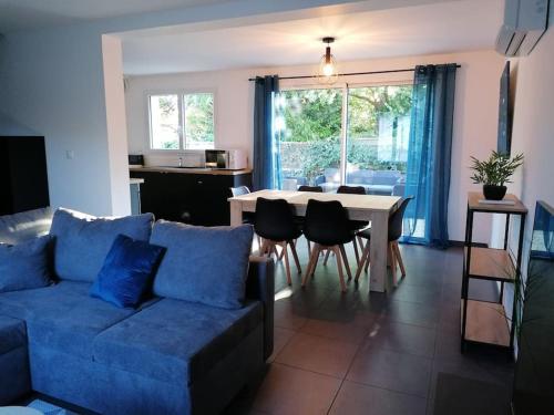 ein Wohnzimmer mit einem blauen Sofa und einem Tisch in der Unterkunft Le Caudalie au cœur des vignobles Pessac Léognan in Léognan