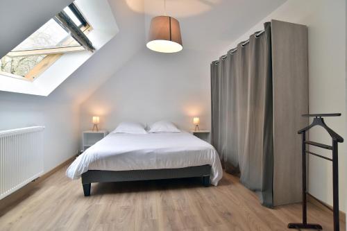 1 dormitorio con cama blanca y ventana en Maison Rive Douce - Charmante maison avec jardin, en Plouër-sur-Rance