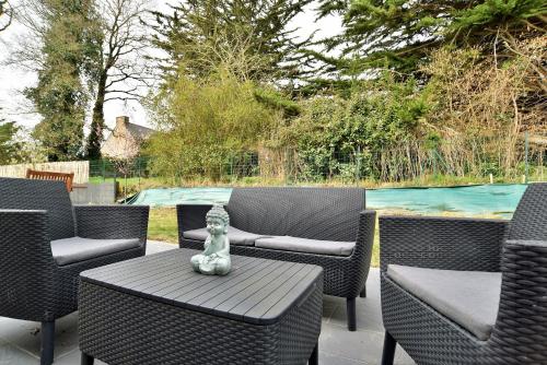 un patio con sillas y una mesa con un jarrón. en Maison Rive Douce - Charmante maison avec jardin, en Plouër-sur-Rance