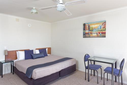 a bedroom with a bed and a table with chairs at BK's Rotorua Motor Lodge in Rotorua