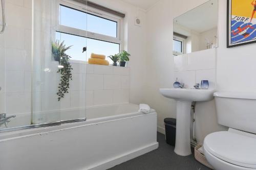 a white bathroom with a tub and a sink at Prime Location Stylish 4-bed House Near Trent Br in Nottingham