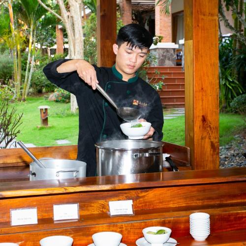 Ein Mann rührt in einer Schüssel in einem Topf. in der Unterkunft Nadine Phu Quoc Resort & Spa in Phu Quoc