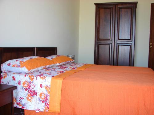 a bed with an orange blanket and pillows on it at Borgo Nicoletta Case per le vacanze in Filandari