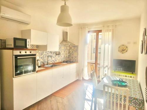 a kitchen with white cabinets and a table in it at CLhome: 3 minuti dal mare in Alghero