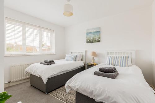 two beds in a room with white walls and a window at Leap House in Wareham