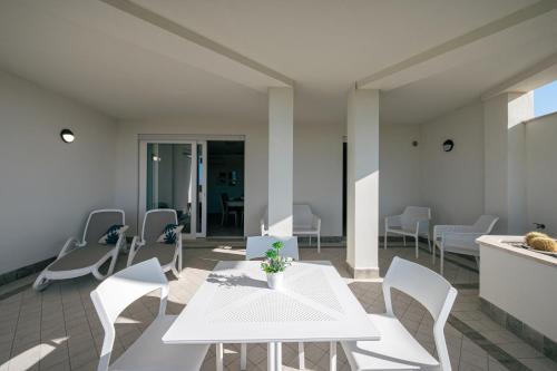 a dining room with white tables and chairs at Milena Suite Apartments in Alghero