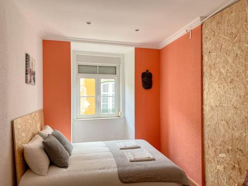 a bedroom with orange walls and a bed with a window at Home Mais Queimada in Lisbon