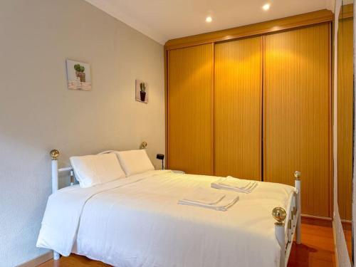 a bedroom with a white bed and a wooden cabinet at Home Mais Queimada in Lisbon