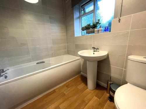 La salle de bains est pourvue d'un lavabo, d'une baignoire et de toilettes. dans l'établissement Spacious 4bed With Private Parking, à Lincolnshire
