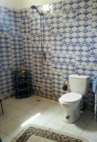 baño con aseo y azulejos azules y blancos en Maison Manour, chambre 'Tribal', en Mbour